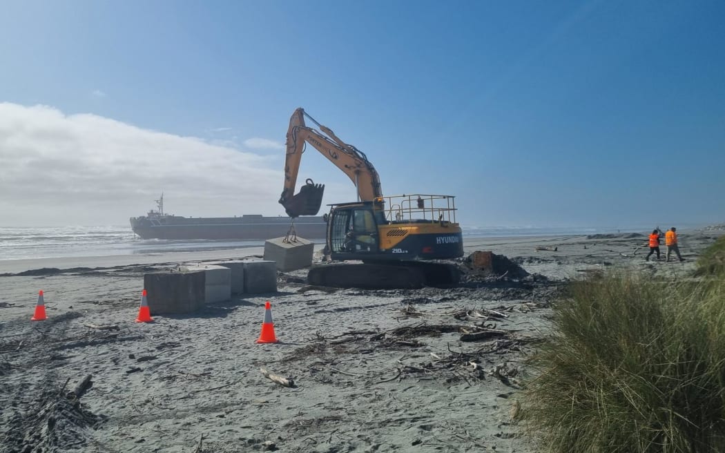 A digger moving concrete blocks that will be used to help stabilise the stranded barge on Monday September 2.