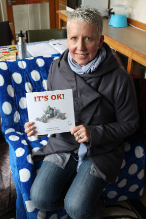Photo of Jo Heslop with the book she has written, "It's OK".
