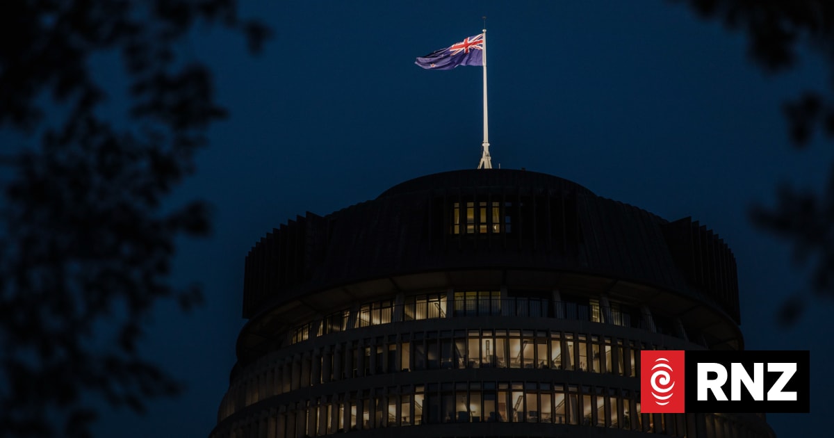 The top of a round government building with a flag flying against a dark blue evening sky.