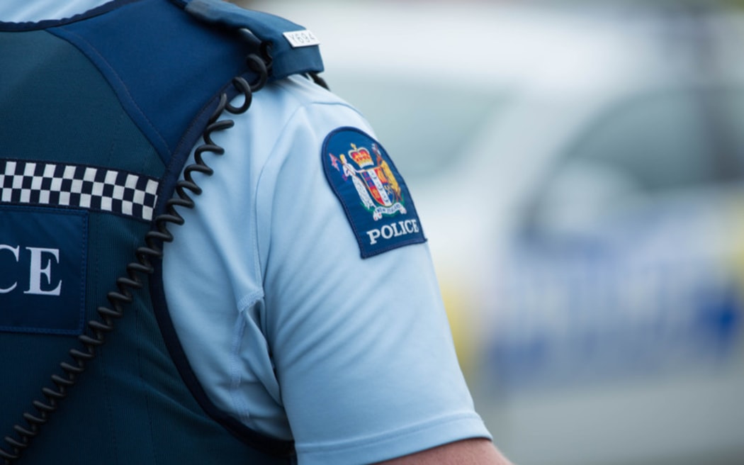 Close up of a police officer at an incident on a residential street. 6 July 2016.