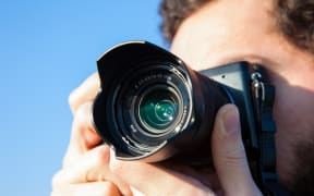 A photographer holds up his camera to take a shot (file)