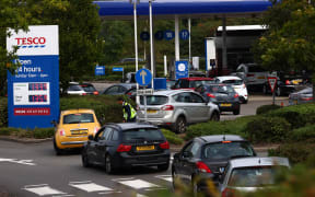 A security guard assists drivers queuing to fill up at a Tesco petrol station in Camberley, west of London, on 26 September 2021.