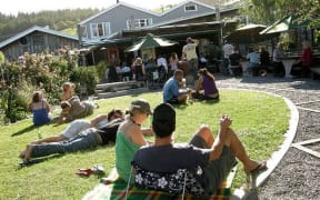 The Leigh Sawmill Cafe front lawn with people sitting in the sun.