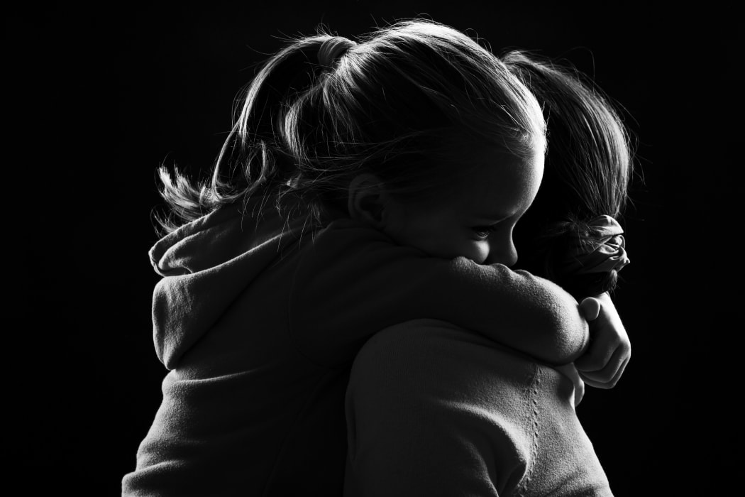 Black and white image of a little girl hugging her mother