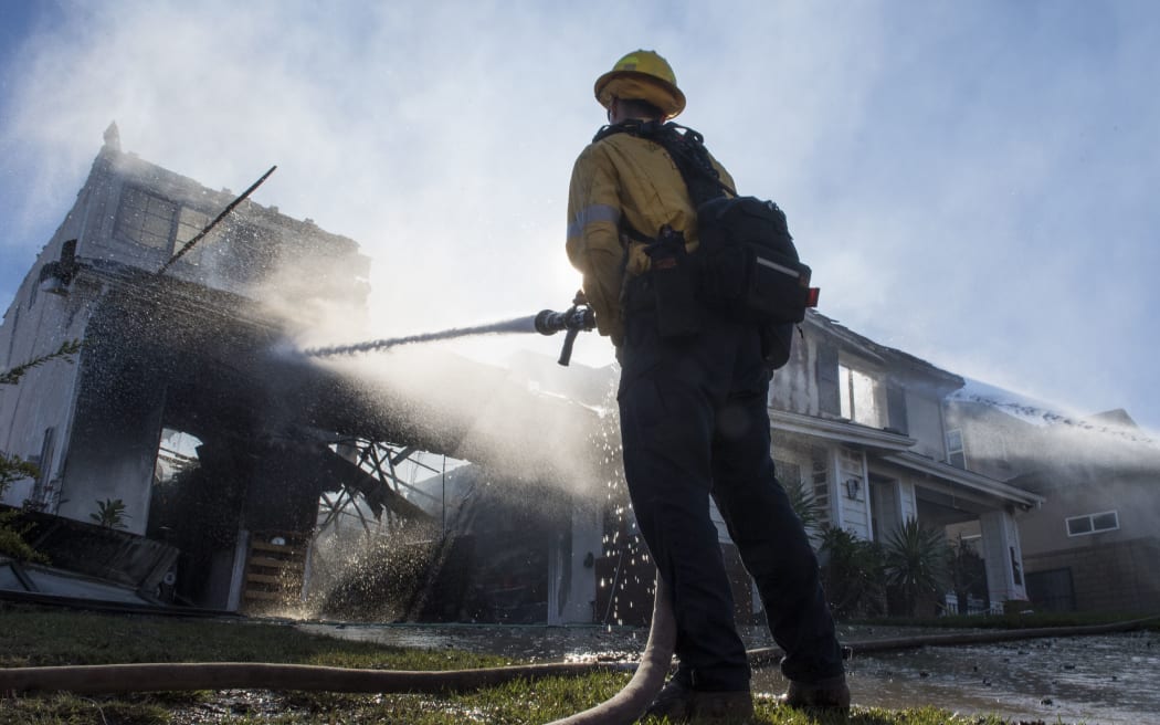 Firefighters hose down a burning house during the Tick Fire in Agua Dulce near Santa Clarita, California on October 25, 2019.