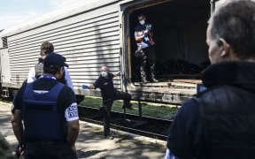 Monitors from the Organization for Security and Cooperation in Europe (OSCE) inspect a refrigerator wagon containing the remains of victims from Flight MH17.