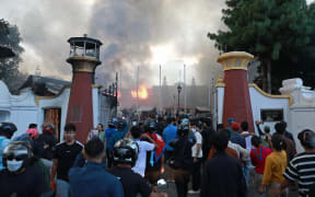 People crowd as smoke billows from the burning President House, set ablaze by protesters in Kathmandu on September 9, 2025, a day after a police crackdown on demonstrations over social media prohibitions and corruption by the government. Nepal's president called for national unity on September 9, after two days of violent protests, including rallies against a government ban on social media that forced the prime minister to resign and left at least 19 people dead. (Photo by Prabin RANABHAT / AFP)