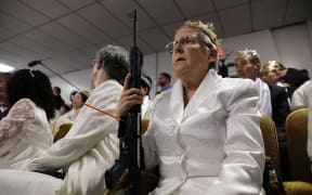 NEWFOUNDLAND, PA - FEBRUARY 28: A woman holds an AR-15 rifle during a ceremony at the World Peace and Unification Sanctuary on February 28, 2018 in Newfoundland, Pennsylvania. The controversial church, which is led by the son of the late Rev. Sun Myung Moon, believes the AR-15 symbolizes the "rod of iron" in the biblical book of Revelation, and it has encouraged couples to bring the weapons to a "commitment ceremony" or "Perfection Stage Book of Life Registration Blessing". Officials in the rural area in the Pocono Mountains have reportedly told elementary school parents that their children will be relocated on Wednesday to accommodate the AR-15 ceremony. The semiautomatic rifles are similar to the weapon used in a Florida high school shooting on February 14.   Spencer Platt/Getty Images/AFP (Photo by SPENCER PLATT / GETTY IMAGES NORTH AMERICA / Getty Images via AFP)