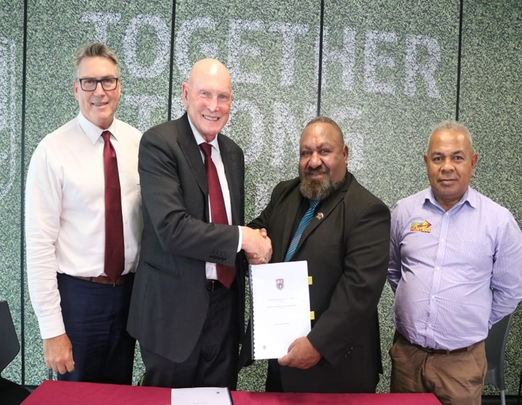 QRL Chairman Bruce Hatcher (2L) and PNGRFL Chairman Sandis Tsaka shake hands after signing a new participation agreement.