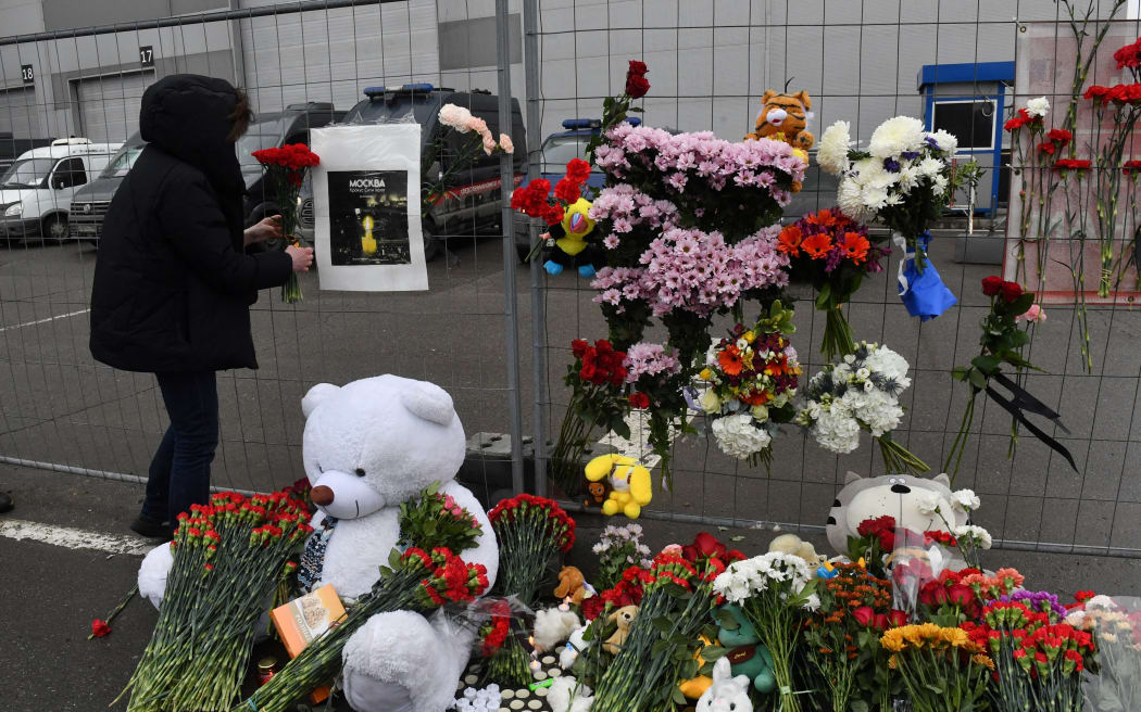 A woman lays flowers at a makeshift memorial in front of the Crocus City Hall, a day after a gun attack in Krasnogorsk, outside Moscow, on March 23, 2024.