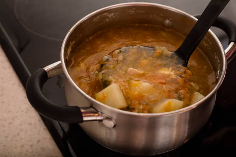 Chicken soup in a saucepan on the stove.