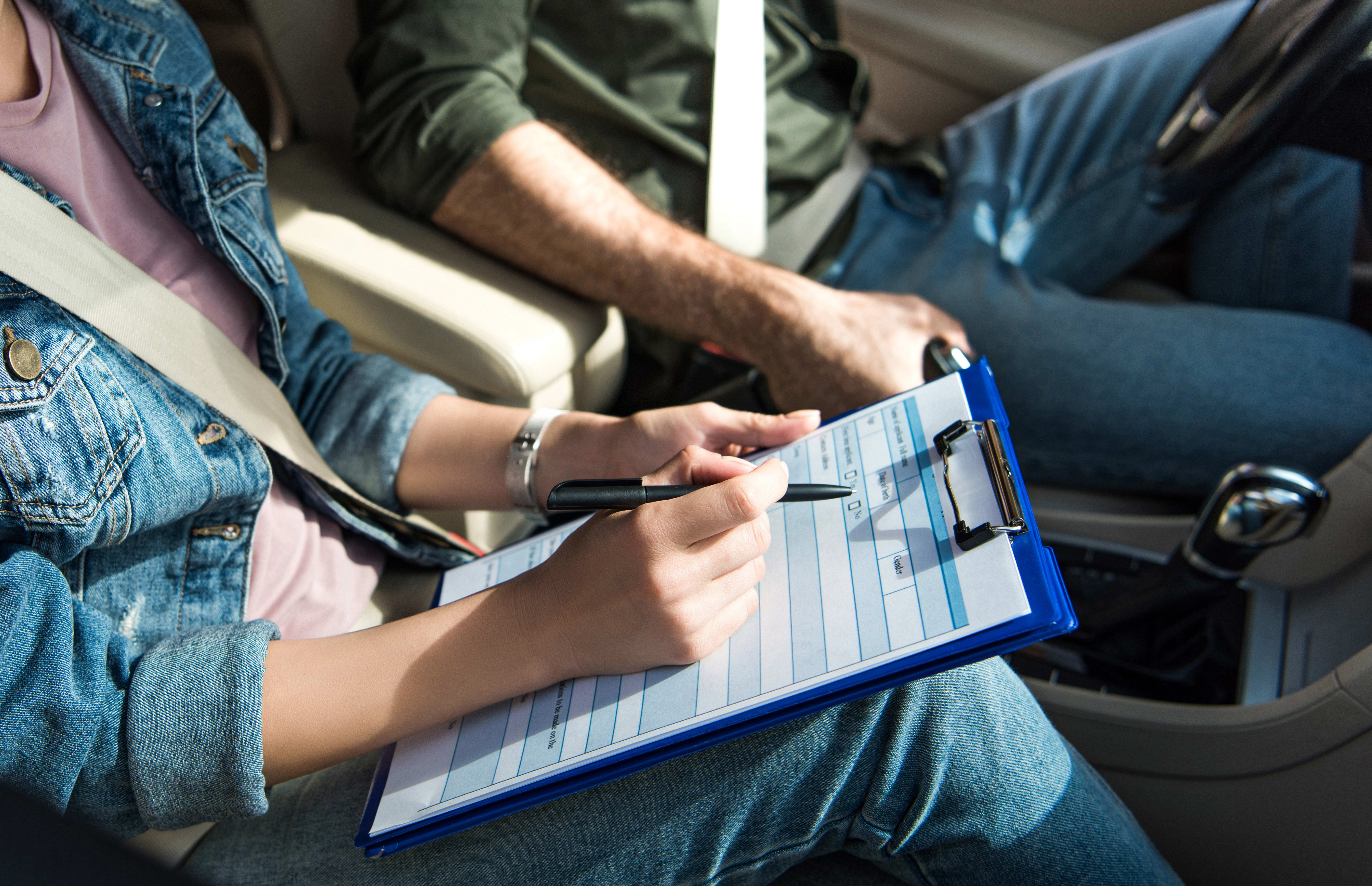 cropped image of student and teacher in car at driving test