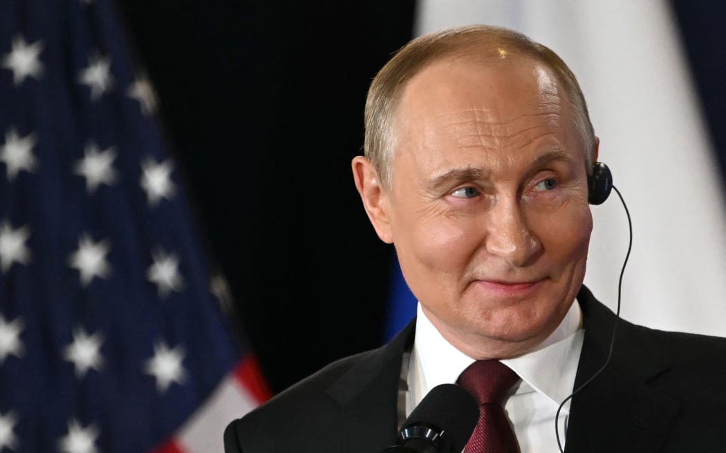 Russian President Vladimir Putin smiles during a joint press conference with US President Donald Trump (out of frame) after participating in a US-Russia summit on Ukraine at Joint Base Elmendorf-Richardson in Anchorage, Alaska, on August 15, 2025. (Photo by ANDREW CABALLERO-REYNOLDS / AFP)