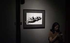 A woman uses her phones near "Golf Sale" by English street artist Banksy during an exhibition, "Street Art in Blu".