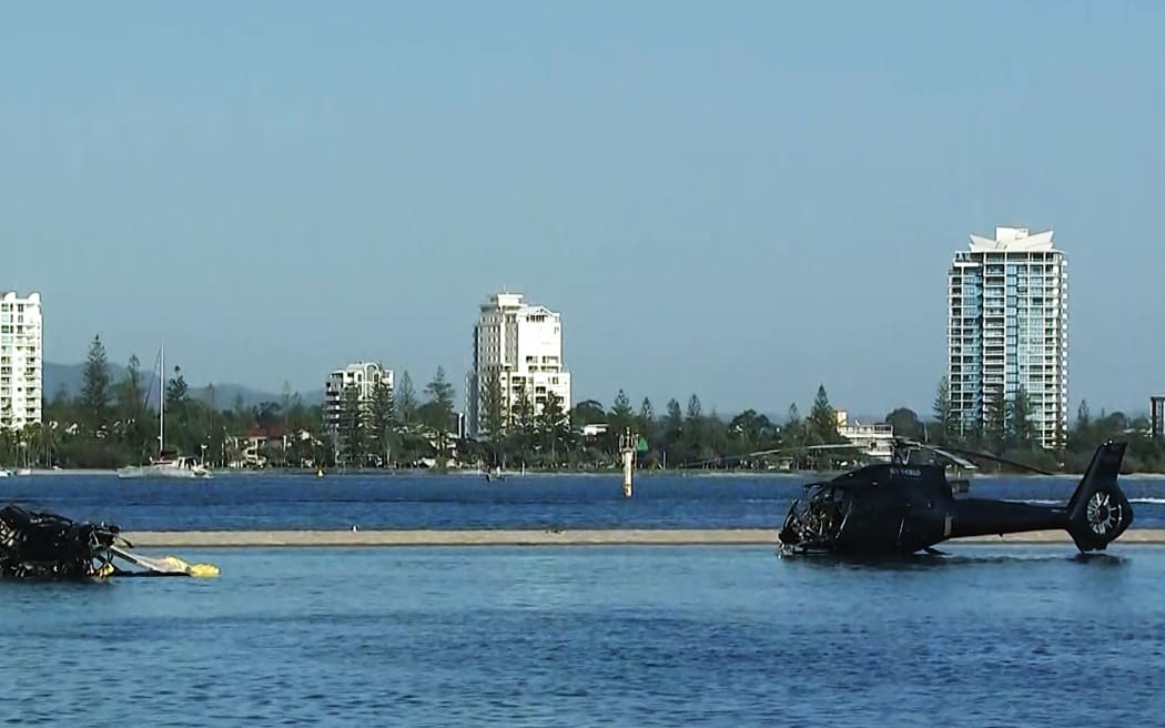 In this handout photo taken and released on January 3, 2023 two helicopters rest in water after colliding in mid-air in Gold Coast on January 2, killing four. A British couple were among four killed in a mid-air collision that left two mangled helicopters on a sandbank near an Australian tourist hotspot, investigators said. (Photo by Handout / ABC / AFP) / - Australia OUT / - AUSTRALIA OUT / RESTRICTED TO EDITORIAL USE - MANDATORY CREDIT “ AFP PHOTO / ABC” - NO MARKETING - NO ADVERTISING CAMPAIGNS - DISTRIBUTED AS A SERVICE TO CLIENTS