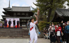 Torch bearer carrying an Olympic flame arrives at Horyu-ji, UNESCO World Heritage site Buddhist temple, in Ikaruga Town, Nara Prefecture on April 12, 2021.
