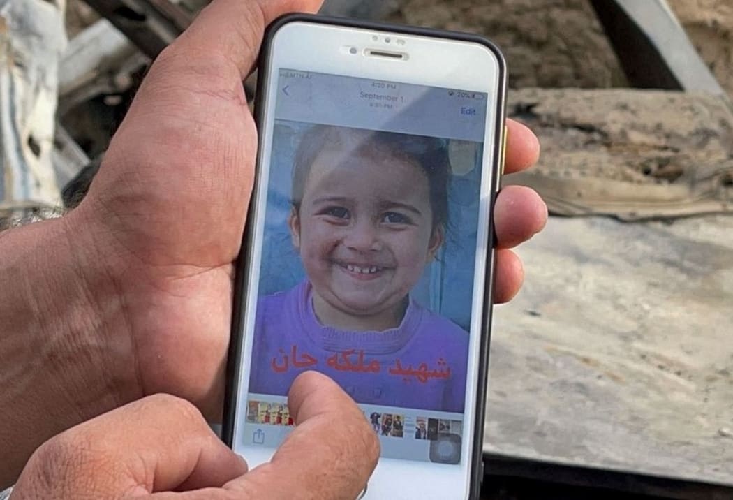 A person shows a photo of one of the family members of Zemari Ahmadi outside their family house after a drone strike in Kabul, Afghanistan. Zemari Ahmadi and nine members of his family, including seven children, were reported killed in the airstrike on August 29.
