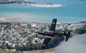 RNZAF plane flying over a costal community.