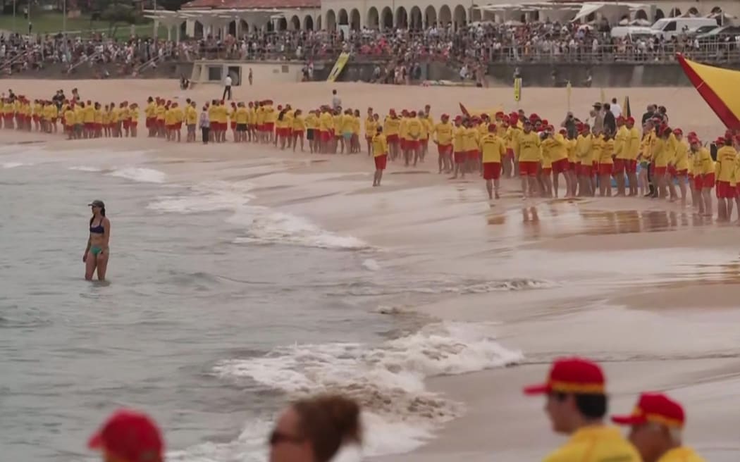 Australian surf lifesavers standing in silence on 20 December, along the entire length of Bondi Beach in Sydney on Friday, in honour of the victims of the 14 December, 2025, Bondi Beach shooting attack.