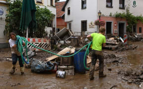Local residents clean up a damaged street in Bad Neuenahr-Ahrweiler, western Germany, on July 16, 2021, after heavy rain hit.