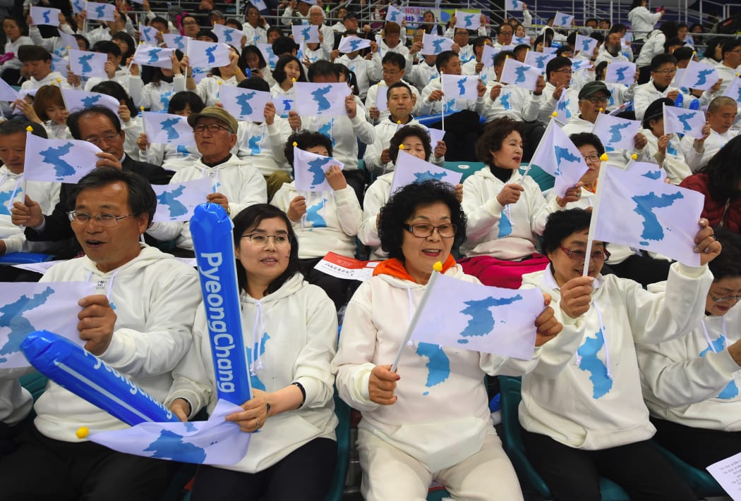 This file photo taken on April 06, 2017 shows South Korean fans waving "unification flags" as they cheer for North Korean players during the IIHF women's world ice hockey championships division II group A competition match between South Korea and North Korea in Gangneung.
