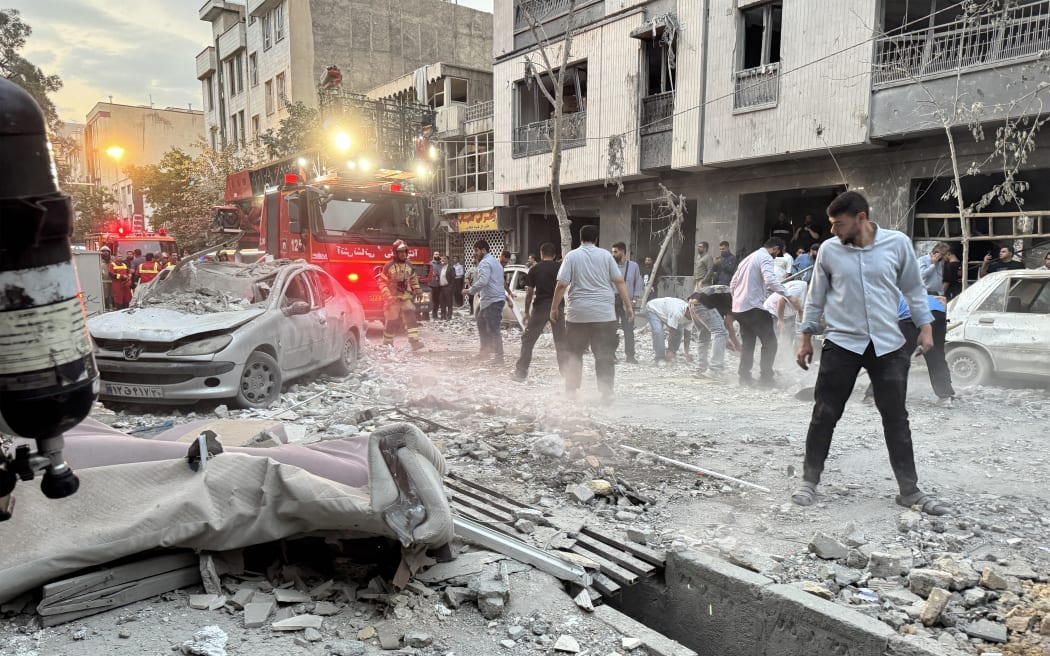 People gather outside a building that was hit by an Israeli strike in Tehran on 13 June, 2025.