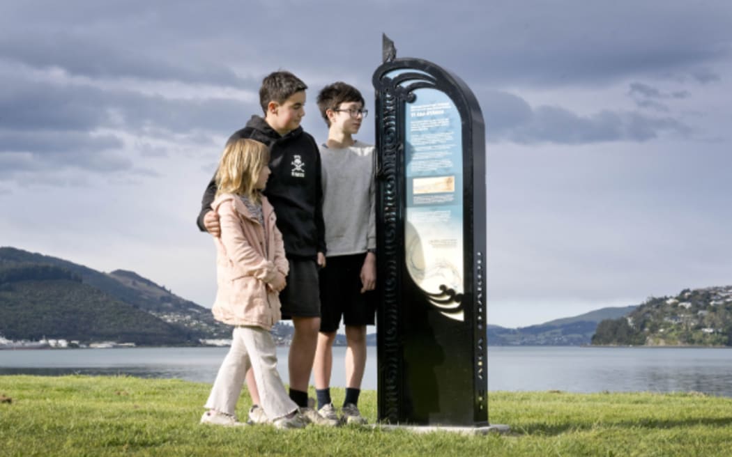 Kuini Parker, 6, Tama Parker (centre), 13, and Robin Luff, 13, read a tohu whenua (cultural marker) near the harbour teeth which teaches them about when different iwi arrived in the area.