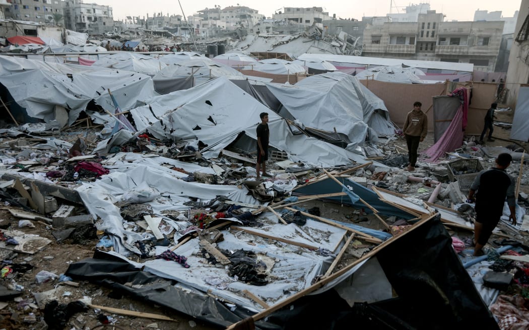 Palestinians are seen surveying the area where displaced people had set up their tent homes, following an Israeli military strike in Gaza City, on November 22, 2025. Gaza's civil defence agency said 21 people were killed and dozens more wounded in multiple Israeli air strikes on the Palestinian territory on November 22. (Photo by Omar AL-QATTAA / AFP)