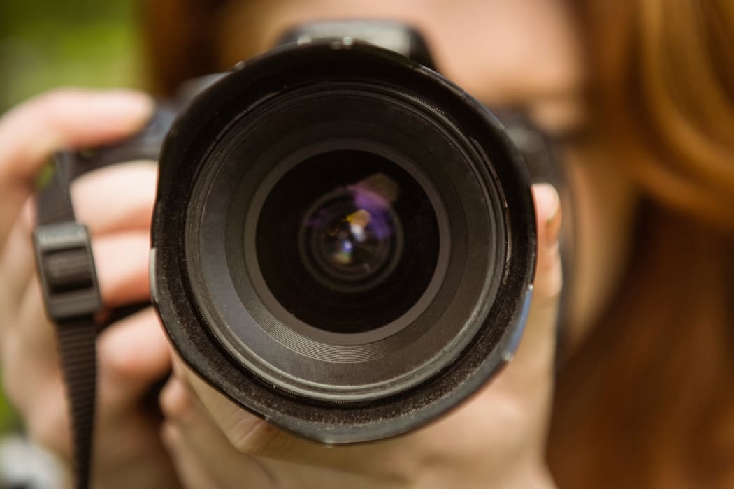 A photographer holds up her camera to take a shot (file)