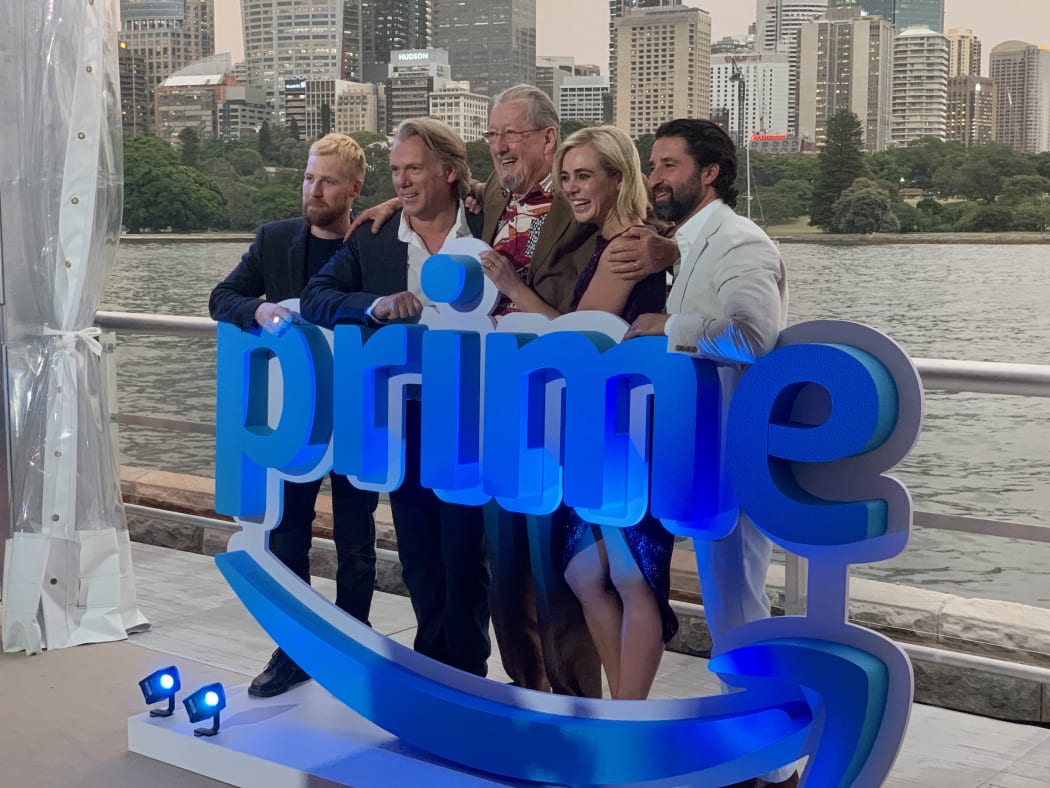 The cast of Back to the Rafters (Angus McLaren, Erik Thomson, Michael Caton, Jessica Marais and George Houvardas), reunited on Sydney’s waterfront by Amazon Prime.