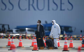 A passenger, left, disembarks from the Diamond Princess at Yokohama on Wednesday 19 February 2020.