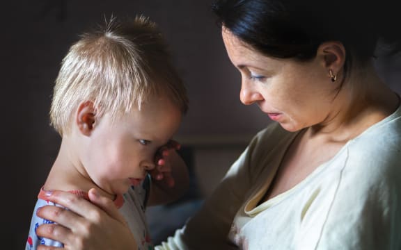 A photo of a mother comforting a small boy who looks distressed