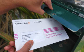 A Census 2023 ltter being removed from a letterbox.