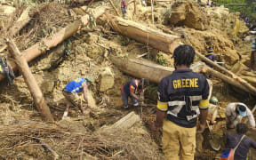 In this image supplied by the International Organization for Migration, villagers search amongst the debris from a landslide in the village of Yambali in the Highlands of Papua New Guinea, Monday, May 27, 2024. (Mohamud Omer/International Organization for Migration via AP)