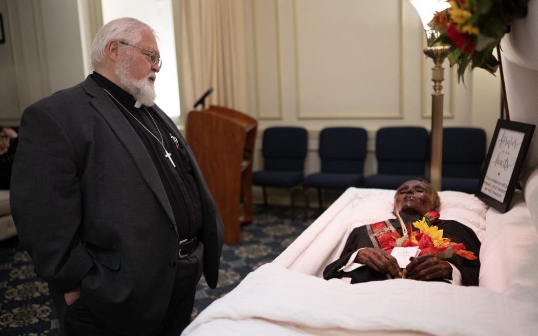 Reverend Robert Whitmer visits the body of  'Stoneman Willie' (James Murphy), during his funeral service in Reading, Pennsylvania, on October 7, 2023. "Stoneman Willie" died in a Pennsylvania jail more than 100 years ago after being arrested for pickpocketing. Upon his arrest, he provided a fake name, and later died of kidney failure at the Berks County Prison. The body has been on display to visitors since 1895, but after an investigation of his mummified remains, he has been identified. (Photo by ANDREW CABALLERO-REYNOLDS / AFP)