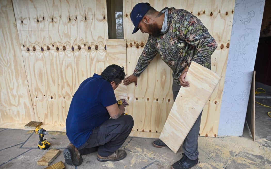 Workers board a window in Tampa, Florida, on October 8, 2024, ahead of Hurricane Milton's expected landfall. - Milton regained power on October 8 to become a Category 5 storm with maximum sustained winds of 165 mph (270 kph) as it barrels towards west-central coast of Florida forecast to make landfall late October 9, according to the National Hurricane Center. (Photo by Miguel J. Rodriguez Carrillo / AFP)