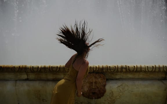 A woman refreshes herself in a fountain at Plaza de Espana, on a hot summer day in Sevilla, Spain.