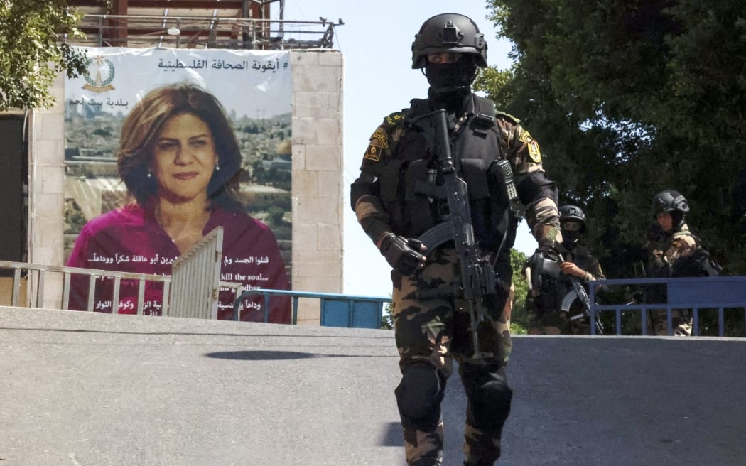 Palestinian security officers stand guard across from a banner depicting slain Palestinian-American journalist Shireen Abu Akleh near the Church of the Nativity in Bethlehem in the occupied West Bank, on July 15, 2022, ahead of the arrival of the US President for an official visit. (Photo by ABBAS MOMANI / AFP)