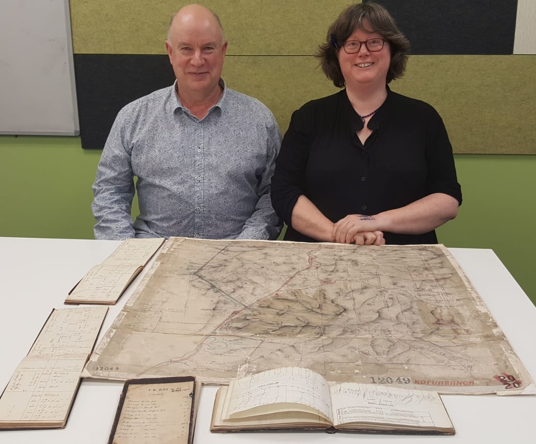 Mike Morris and Alison Midwinter with early surveyors' field notebooks and a hand-drawn survey plan from the Wairarapa.
