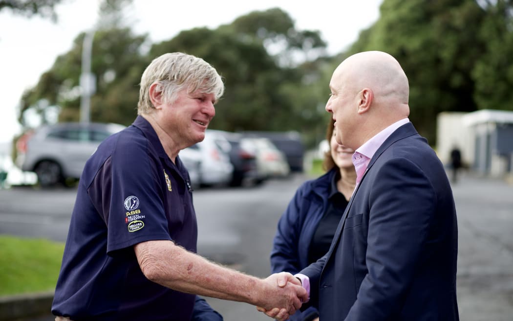 Christopher Luxon shakes hands with a stakeholder at a pre-budget announcement about Surf Lifesaving & Coastguard funding