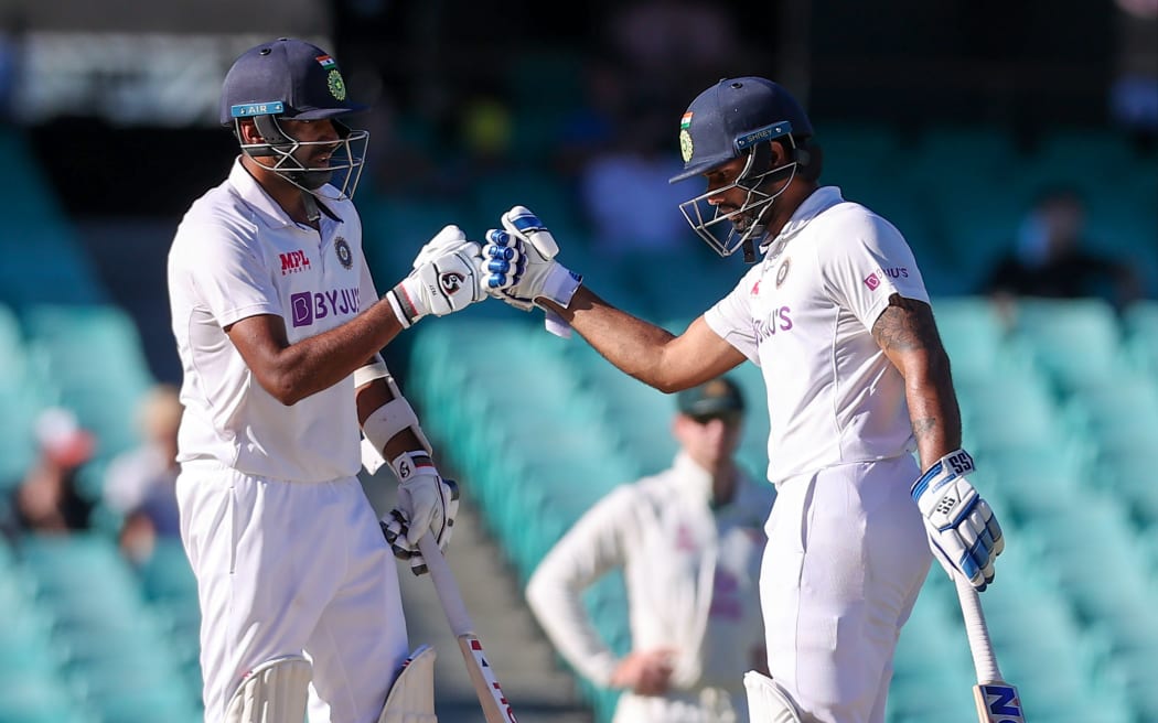 India's Ravichandran Ashwin (L) and teammate Hanuma Vihari touch gloves during the fifth day of the third cricket Test match between Australia and India at the Sydney Cricket Ground (SCG) in Sydney on January 11, 2021.