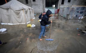 A Palestinian boy attempts to get water out after raining at a camp for displaced people in Rafah, in the southern Gaza Strip where most civilians have taken refuge, on December 13, 2023, as battles continue between Israel and the Palestinian militant group Hamas. Israel came under pressure on December 13 from its allies over its war in Gaza, with key backer the United States criticising its bombing in response to the October 7 attacks as "indiscriminate". (Photo by Mahmud HAMS / AFP)