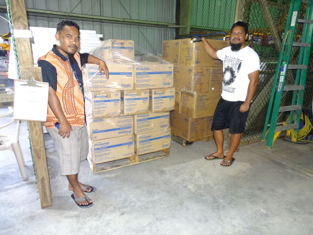 International Organization for Migration warehouse manager Steve Enoch, left, and Ministry of Health and Human Services official Mackneil Abraham with pallets PPEs delivered through US funding