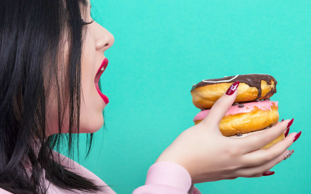 plus size woman with red lips with donuts in her hands getting ready to eat them, on azure background