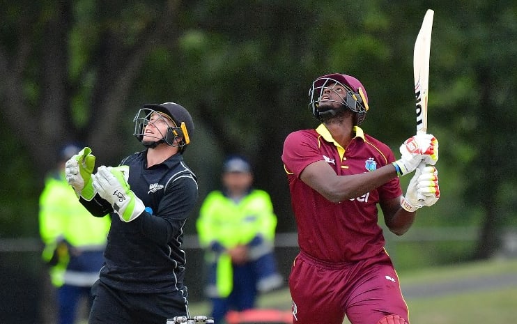 West Indies captain Jason Holder hits the ball into the air and is caught out as New Zealand's wicketkeeper Tom Latham (L) looks on.