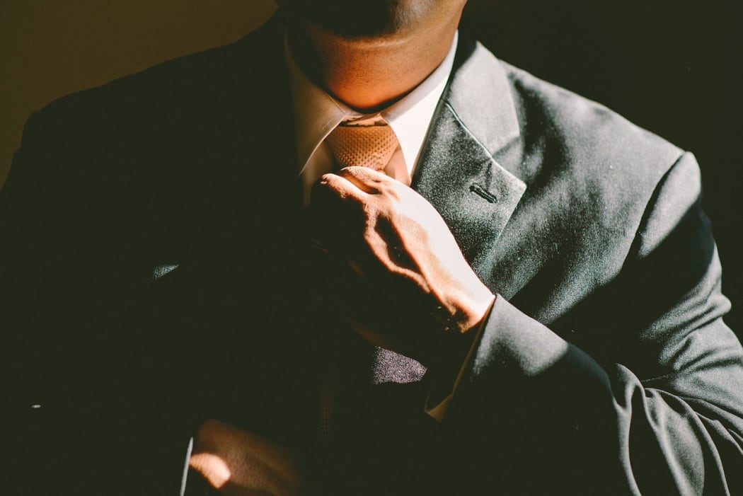 Man in suit adjusts tie