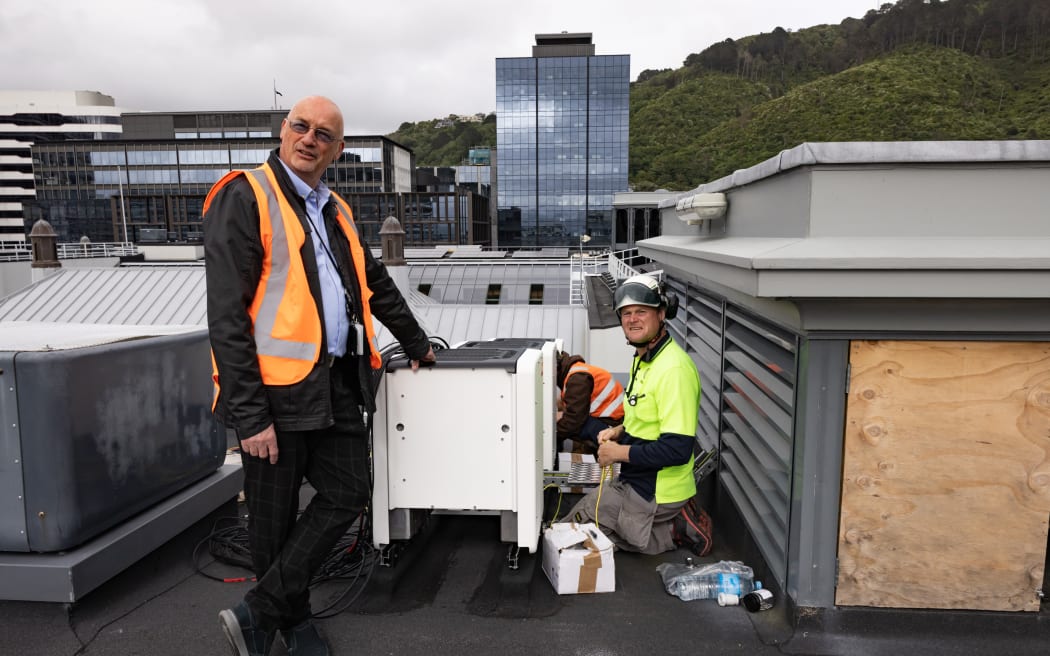 On the roof of Parliament House in Wellington James Hogg from Sunergise adjusts the new SMA inverters. Standing is Steve Barron, Parliament's solar panel project manager. 

.