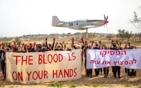 Left-wing activists hold up banners at an anti-war protest held at an Israeli Air Force base in southern Israel. The banners that the activists are holding say "the blood is on your hands" in English and, "stop bombing gaza" in Hebrew.