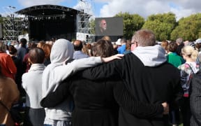 People stand while Yusuf Islam / Cat Stevens sings during the national remembrance service in Christchurch.