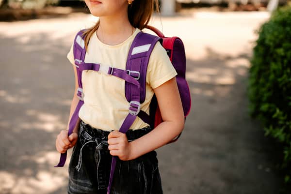 Child wearing backpack and going to school.